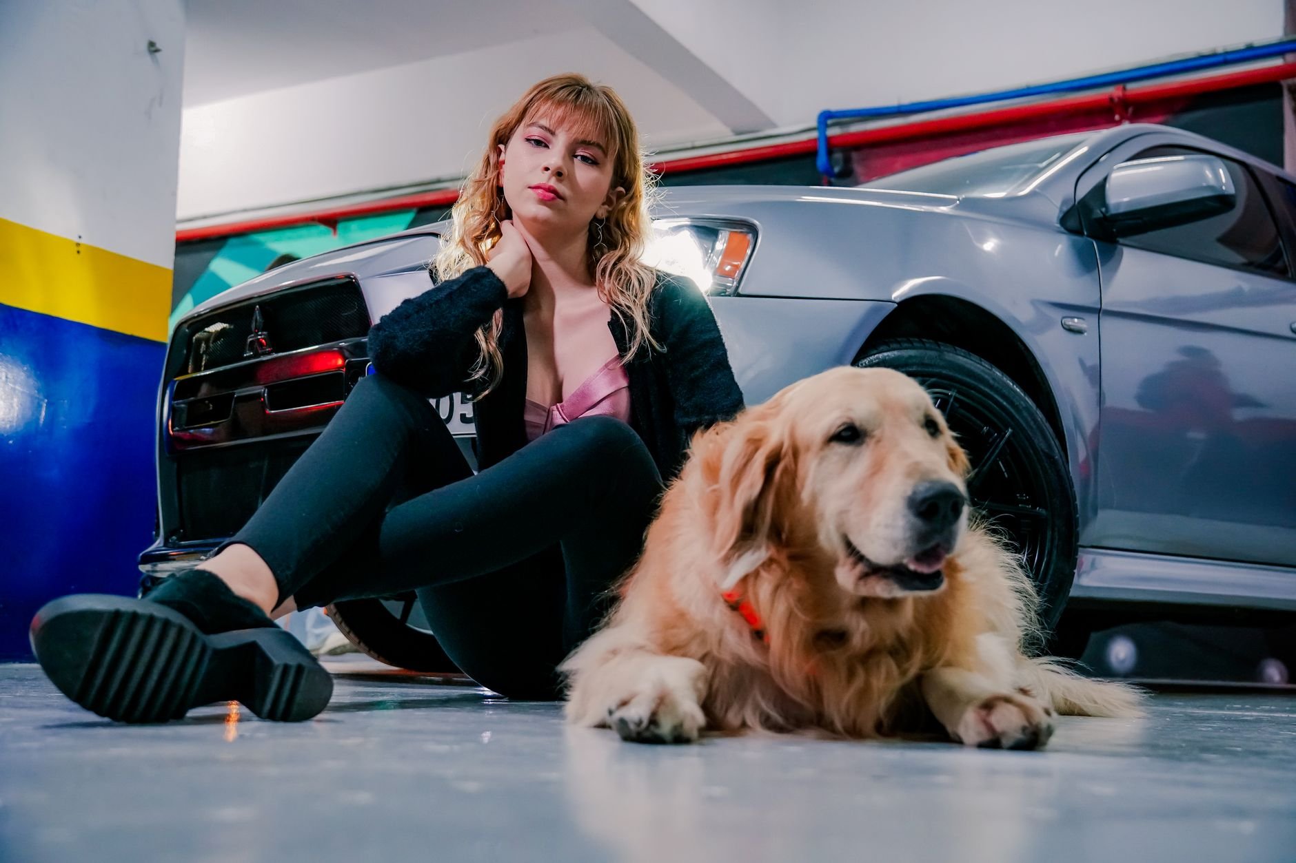 Young woman and golden retriever dog sitting beside a parked car, ready for a road trip.